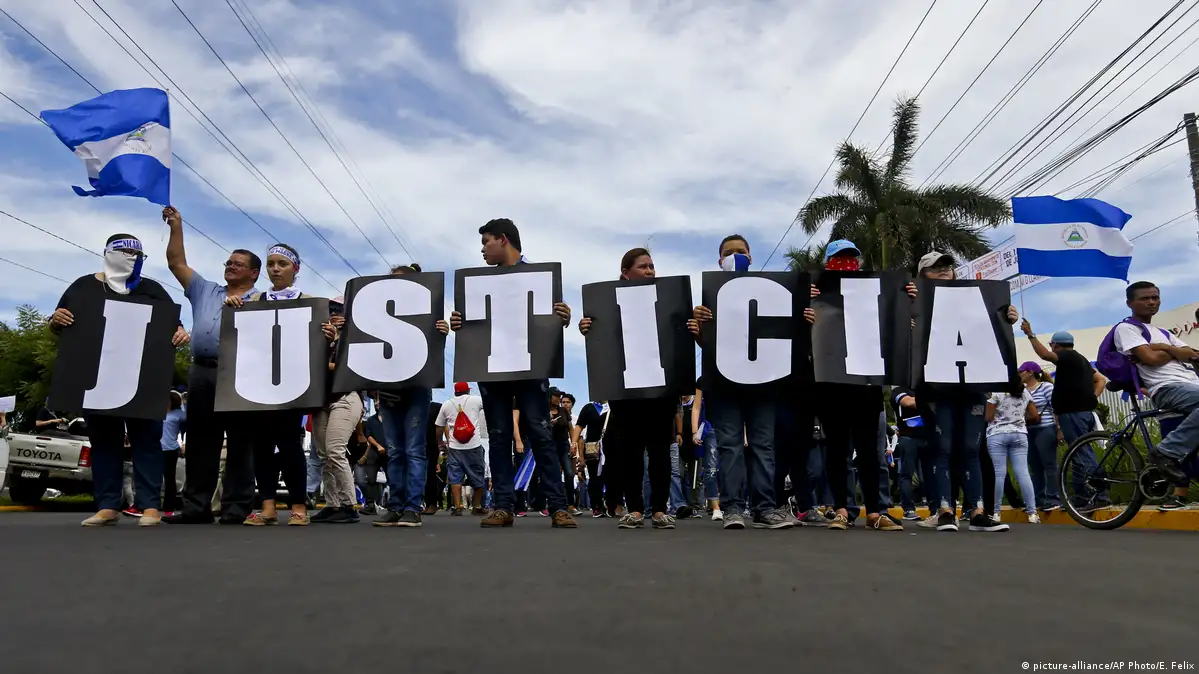 Manifestantes sosteniendo carteles que forman la palabra Justicia en una avenida de Managua