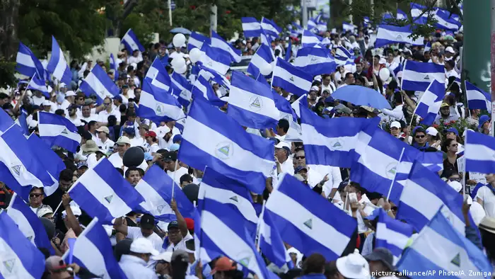 Multitud de manifestantes ondeando cientos de banderas de Nicaragua en una avenida