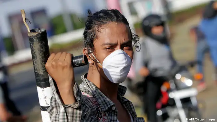 Joven con mascarilla cargando un mortero artesanal al hombro durante una protesta