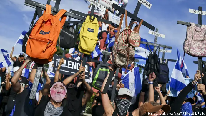 Manifestantes levantando cruces con mochilas de estudiantes asesinados