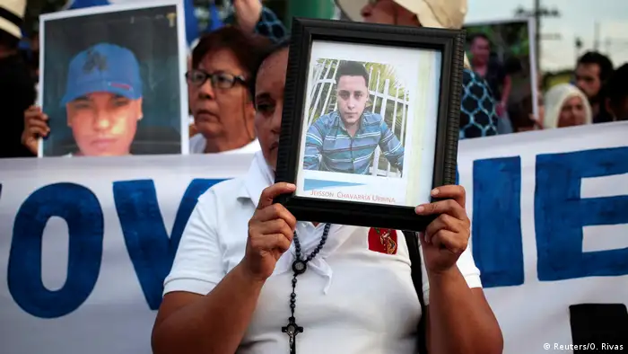 Mujer sosteniendo el retrato enmarcado de una victima de la represion