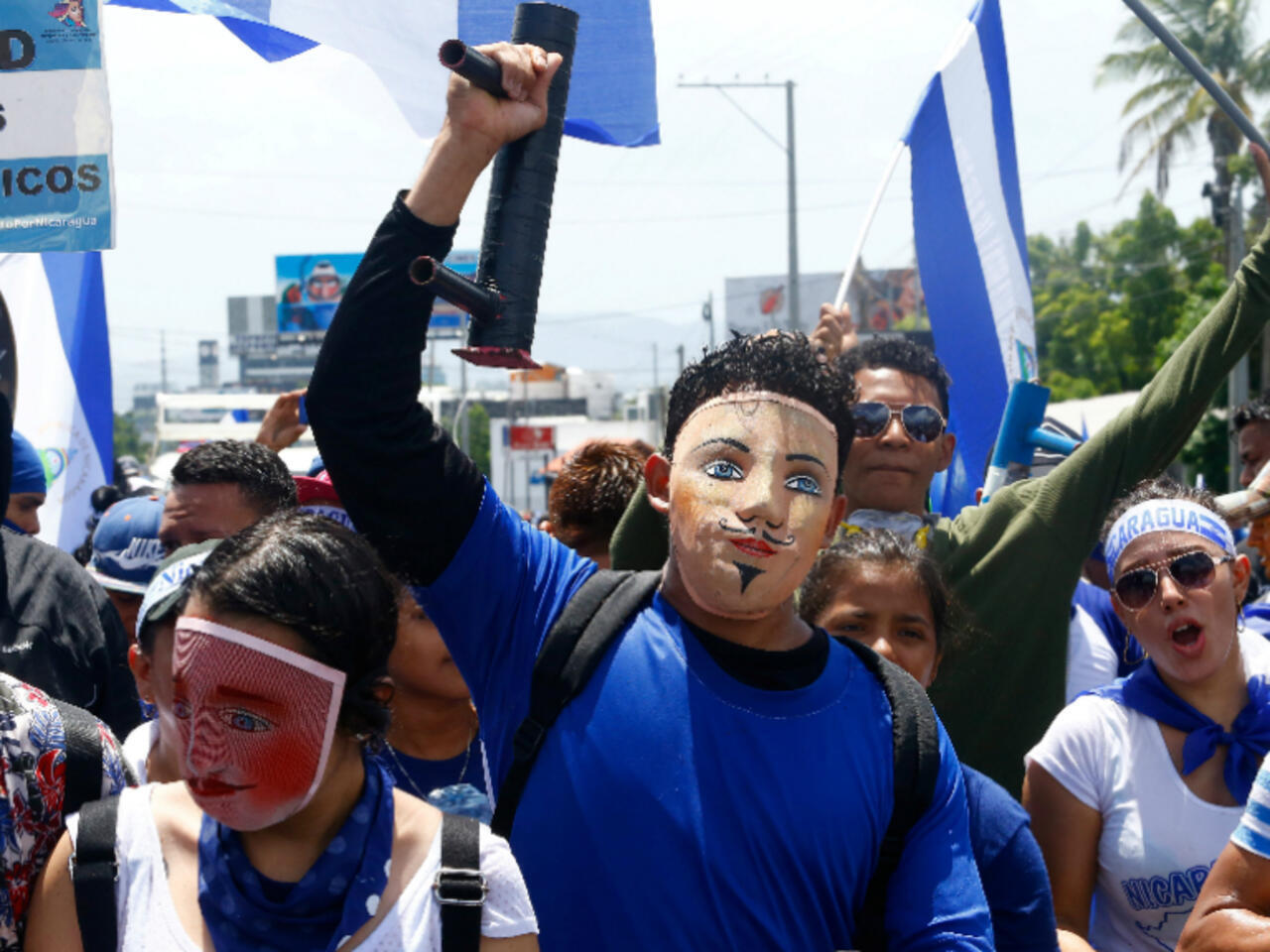 Jóvenes con máscaras tradicionales y morteros artesanales marchando con banderas de Nicaragua